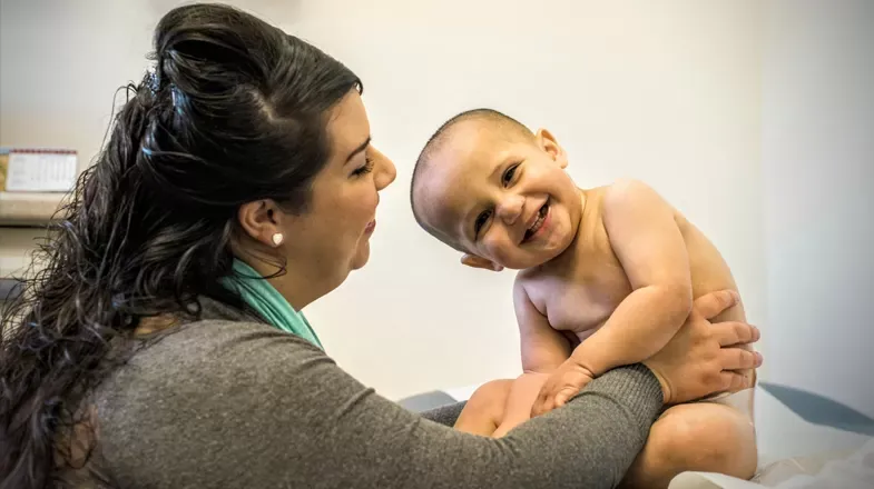 A healthcare worker holds a smiling baby at a safety-net clinic in the United States.